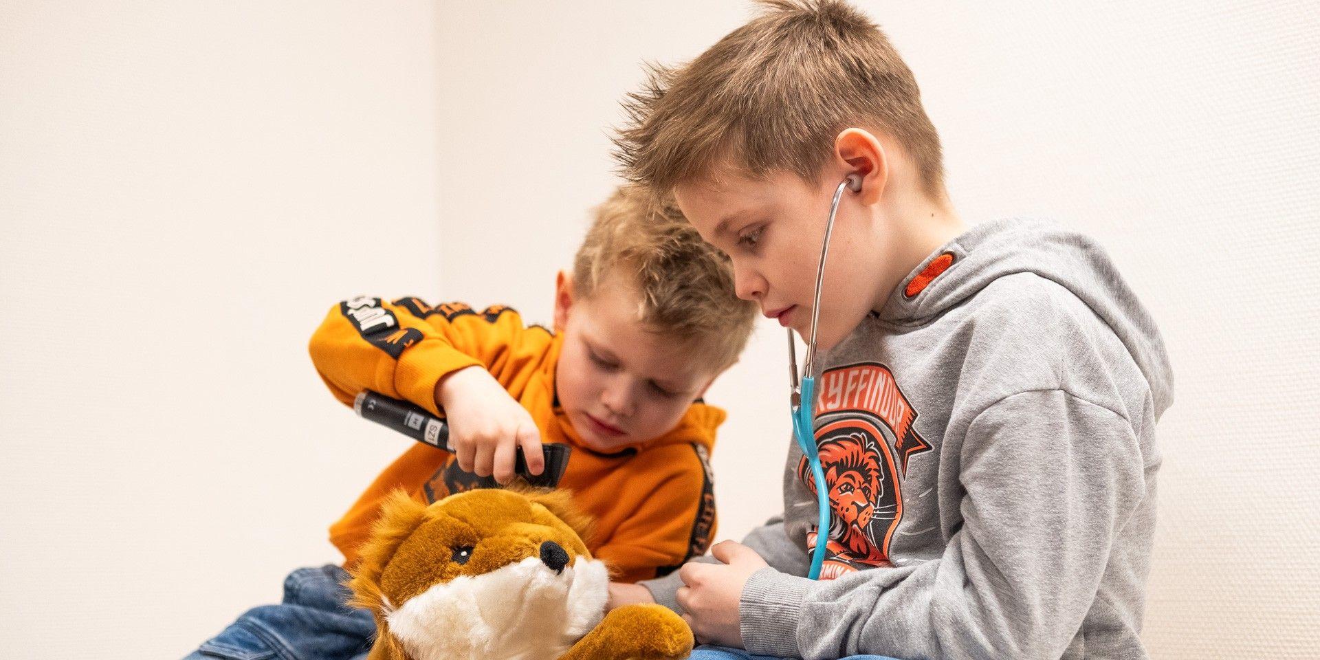 Zwei Kinder untersuchen spielerisch ein Stofftier mit Stethoskop und Ohrenspiegel. Zwei Kinder untersuchen spielerisch ein Stofftier mit Stethoskop und Ohrenspiegel.