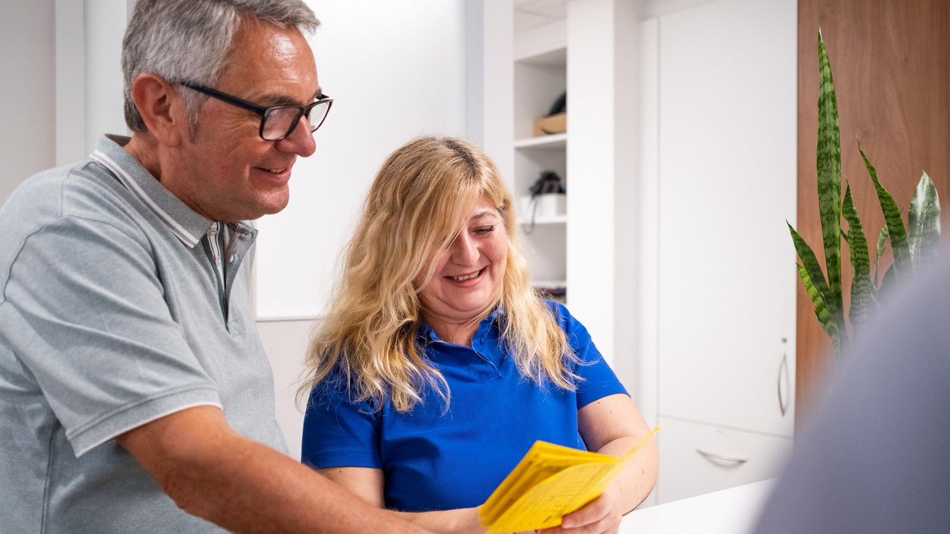 Arzthelferin erklärt einem Patienten seinen Impfausweis. Arzthelferin erklärt einem Patienten seinen Impfausweis.